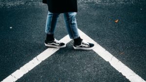A person standing on a white line in a parking lot, dressed in clean shoes.
